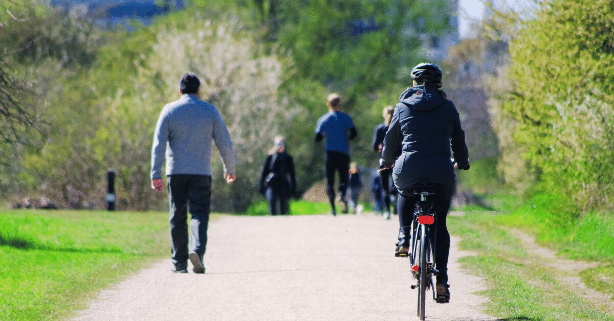 People walking and cycling along a green outdoor path, enjoying gentle movement in nature.