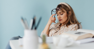 Woman at her desk with eyes closed and glasses in hand — the moment why motivation fails becomes impossible to ignore