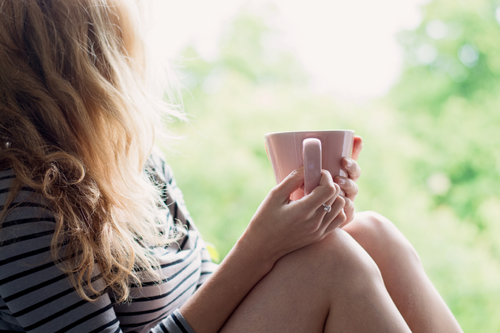 Woman holding a mug by a window taking a quiet moment to reflect