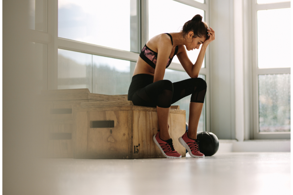 Woman sitting hunched forward with head down showing emotional exhaustion and overwhelm